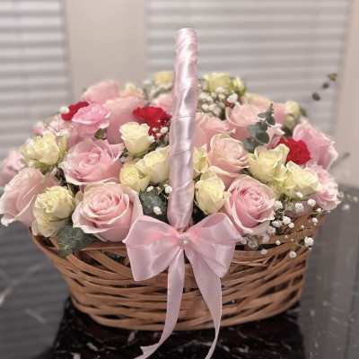 Basket of pink and cream roses with a pink ribbon handle