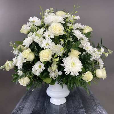 White roses and daisies arranged in a white vase