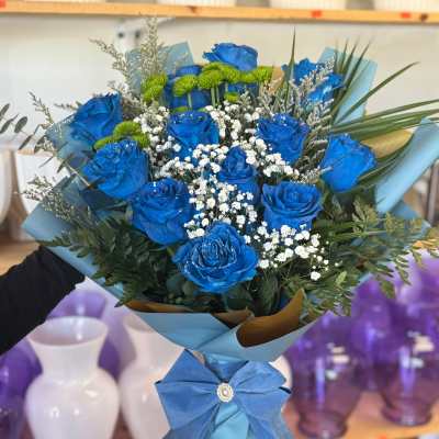 Blue roses with white baby's breath in a wrapped bouquet