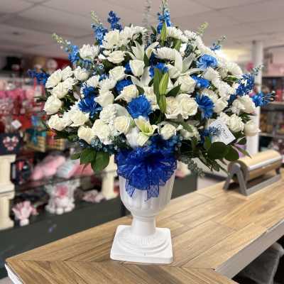 White and blue floral arrangement in a white urn vase