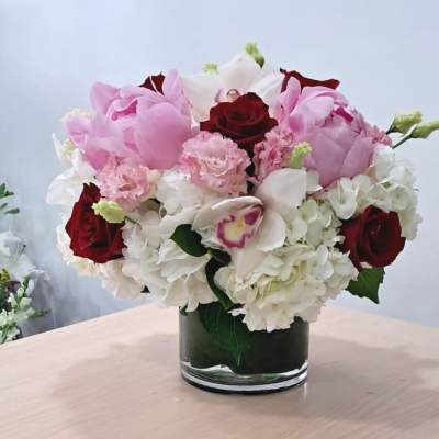 Pink and white bouquet with red roses in a glass vase