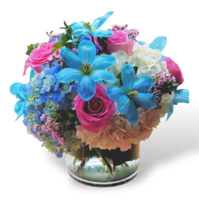 Colorful bouquet of roses, hydrangeas, and blue lilies in a glass vase
