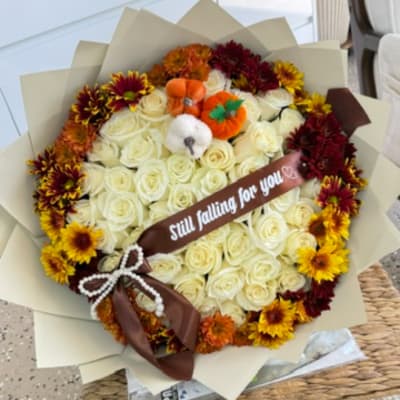 Heart-shaped bouquet of white roses with autumn-colored flowers and pumpkins