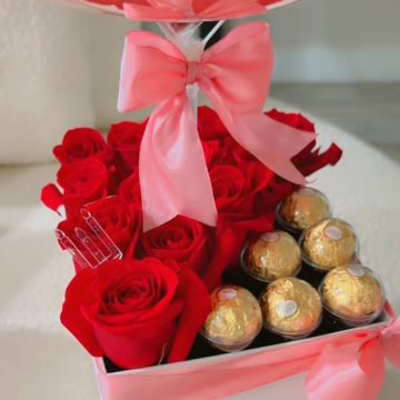 Red roses and gold chocolates in a pink ribboned gift box