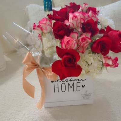 Box of red and pink roses with a wine bottle and ribbon