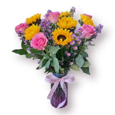 Bouquet of pink roses, yellow sunflowers, and purple filler in a glass vase