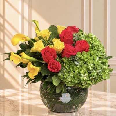 Yellow calla lilies and red and yellow roses in a glass vase