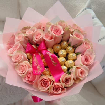 Pink rose bouquet with gold-wrapped chocolates and a satin ribbon