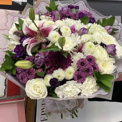 Large bouquet of white, purple, and pink flowers wrapped in paper