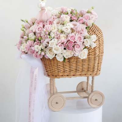 Pink and white rose bouquet in a wicker baby carriage with a small doll topper