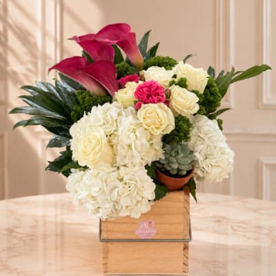 Bouquet of white hydrangeas, cream roses, and magenta calla lilies in a wooden box