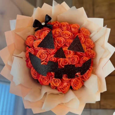 Orange rose bouquet with a black jack-o'-lantern face and bow