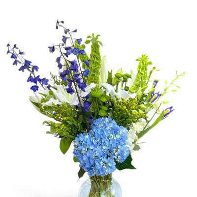 Blue and white mixed flower arrangement in a clear glass vase