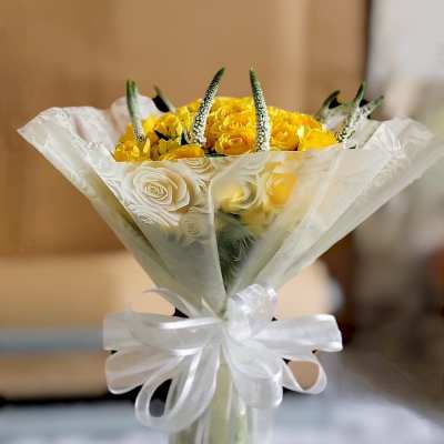 Yellow rose bouquet wrapped in white paper with a ribbon