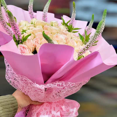 Pink bouquet of pale roses wrapped in pink paper with a heart ribbon