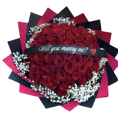 Bouquet of red roses with baby's breath and a "Will you marry me?" ribbon