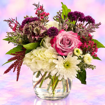Mixed bouquet of pink and white flowers in a clear glass vase