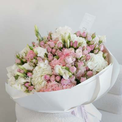 Large bouquet of pink and white roses wrapped in white paper