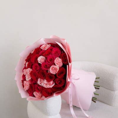 Bouquet of red and pink roses wrapped in pale pink paper