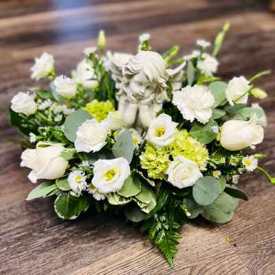 White floral arrangement with a small angel figurine in the center