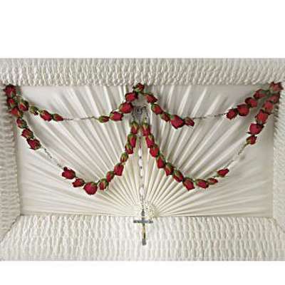 White casket spray with red rose garland and a small cross
