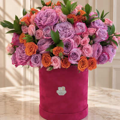 Pink and lavender roses arranged in a magenta hat box