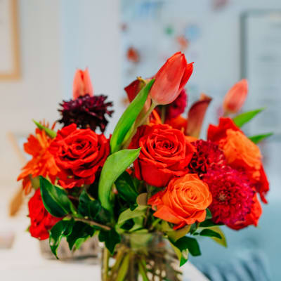 Red and orange flower arrangement in a clear glass vase