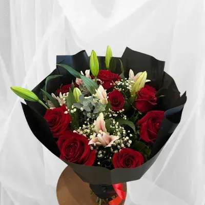 Bouquet of red roses and lilies wrapped in black paper