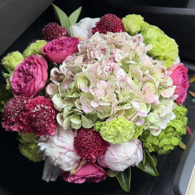 Bouquet of pink and green flowers with a large pale hydrangea cluster