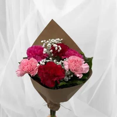 Bouquet of pink and red carnations with baby's breath in brown paper