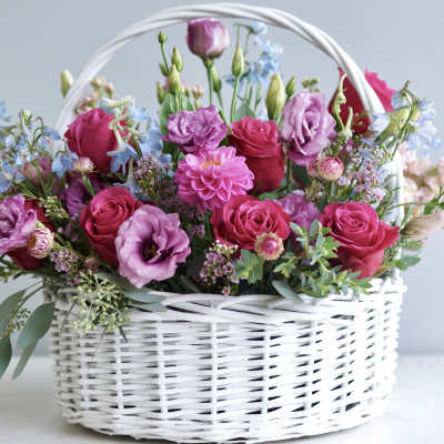 Pink and purple flowers arranged in a white wicker basket