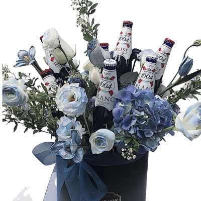 Blue and white flowers arranged with beer bottles in a black hatbox.
