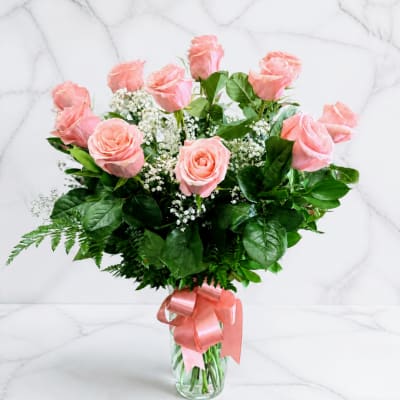 Pink roses in a clear glass vase with a satin ribbon