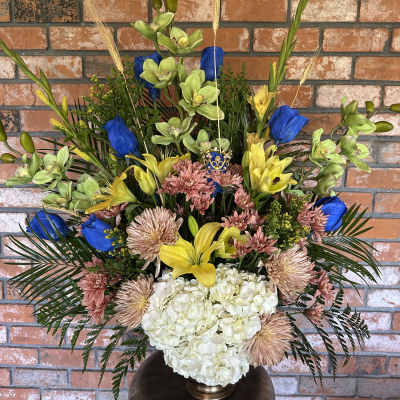 Tall mixed floral arrangement in a vase with blue, yellow, pink, and white blooms