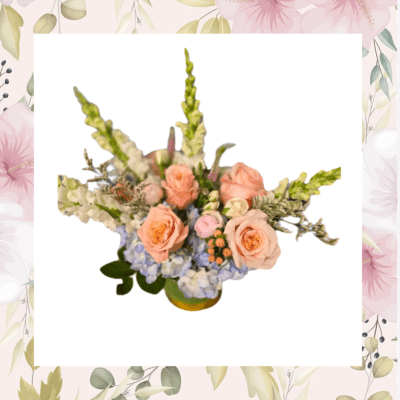 Peach roses and blue hydrangeas in a low floral arrangement