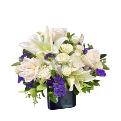 White lilies and roses arranged in a dark vase with purple accents