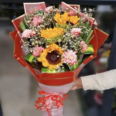 Bouquet of sunflowers and pink daisies wrapped in red paper