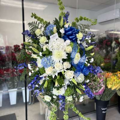 Large blue and white funeral spray on an easel with ribbon