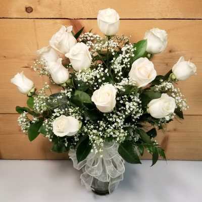 White roses arranged in a glass vase with baby's breath