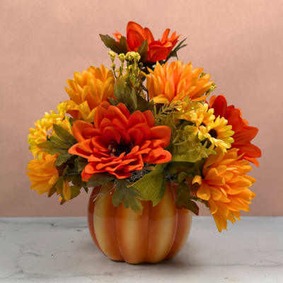 Orange and yellow flower arrangement in a pumpkin-shaped vase