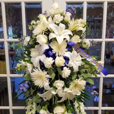 White funeral spray with lilies, roses, and chrysanthemums on a stand