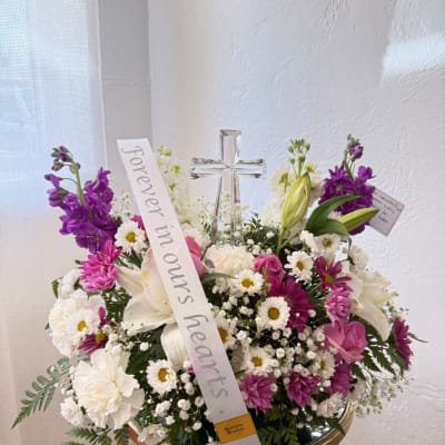 Mixed white and purple floral arrangement with a clear cross centerpiece