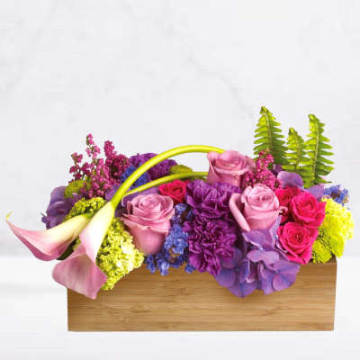 Colorful floral arrangement in a wooden box with pink calla lilies and roses
