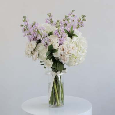 White and blush bouquet in a clear glass vase with a ribbon
