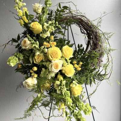 Yellow roses and snapdragons arranged on a wreath stand