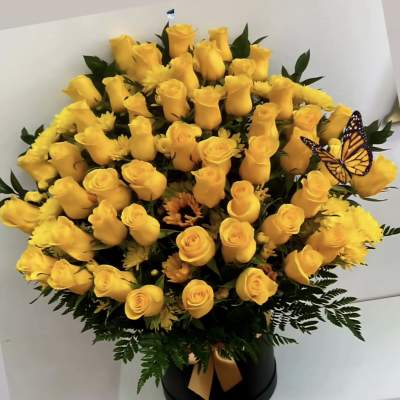 Yellow roses in a black hatbox with a butterfly accent