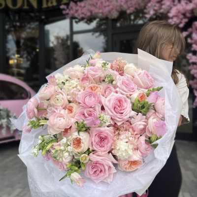 Large bouquet of pink roses and pale mixed blooms wrapped in white paper