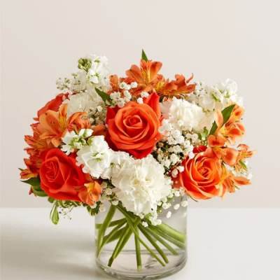 Orange and white flower arrangement in a clear glass vase