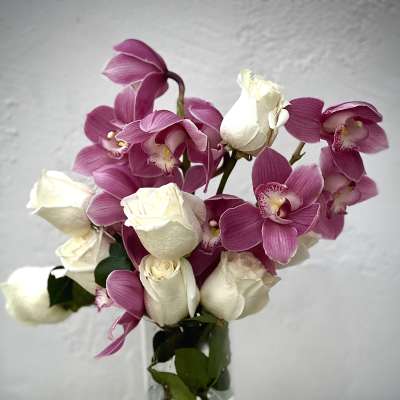 Bouquet of pink orchids and white roses in a clear glass vase