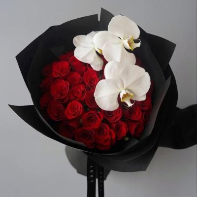 Bouquet of red roses with white orchids wrapped in black paper
